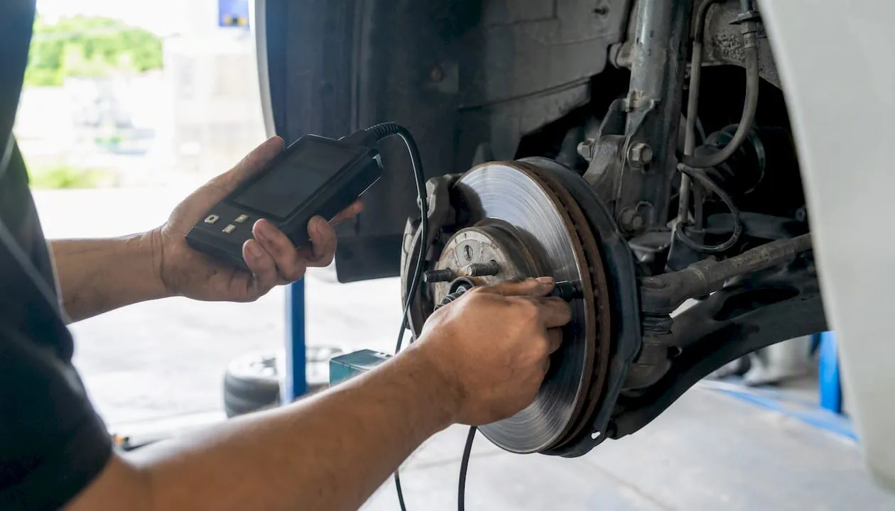 Mechanic's hands inspecting tire and brake disc