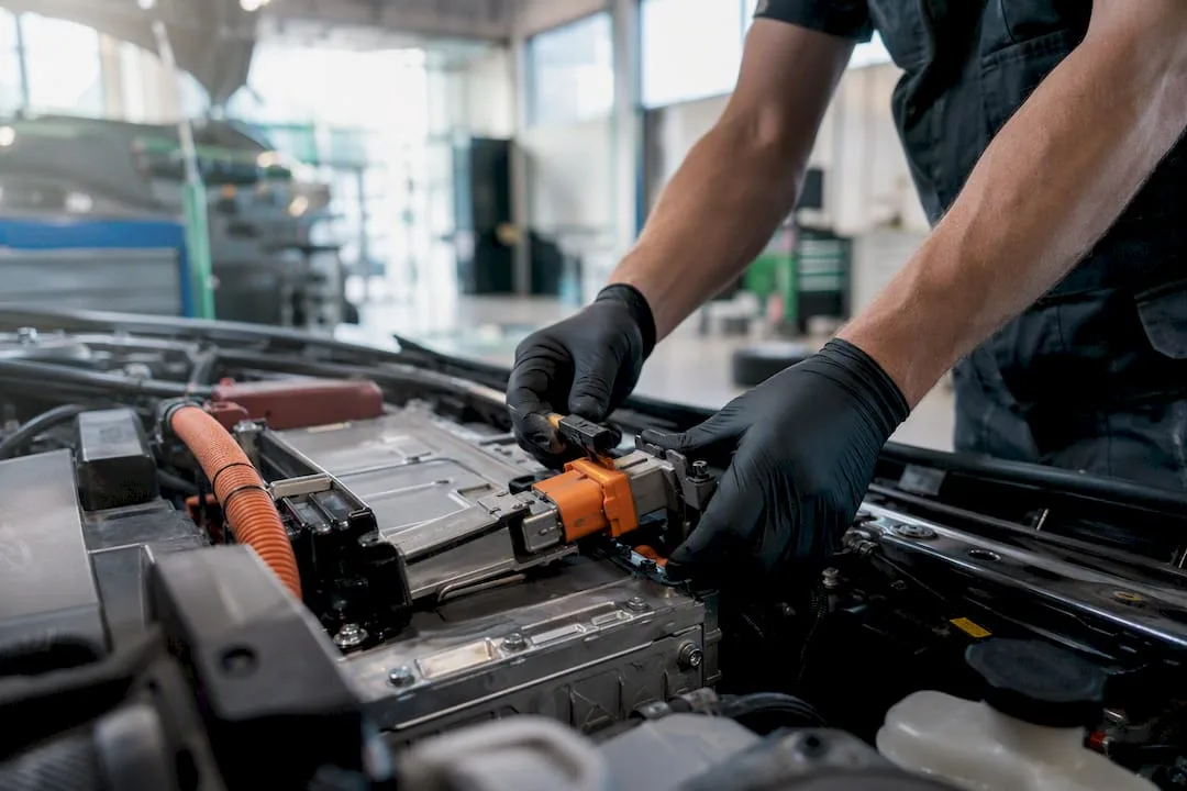 Technician hands disconnecting hybrid battery cable